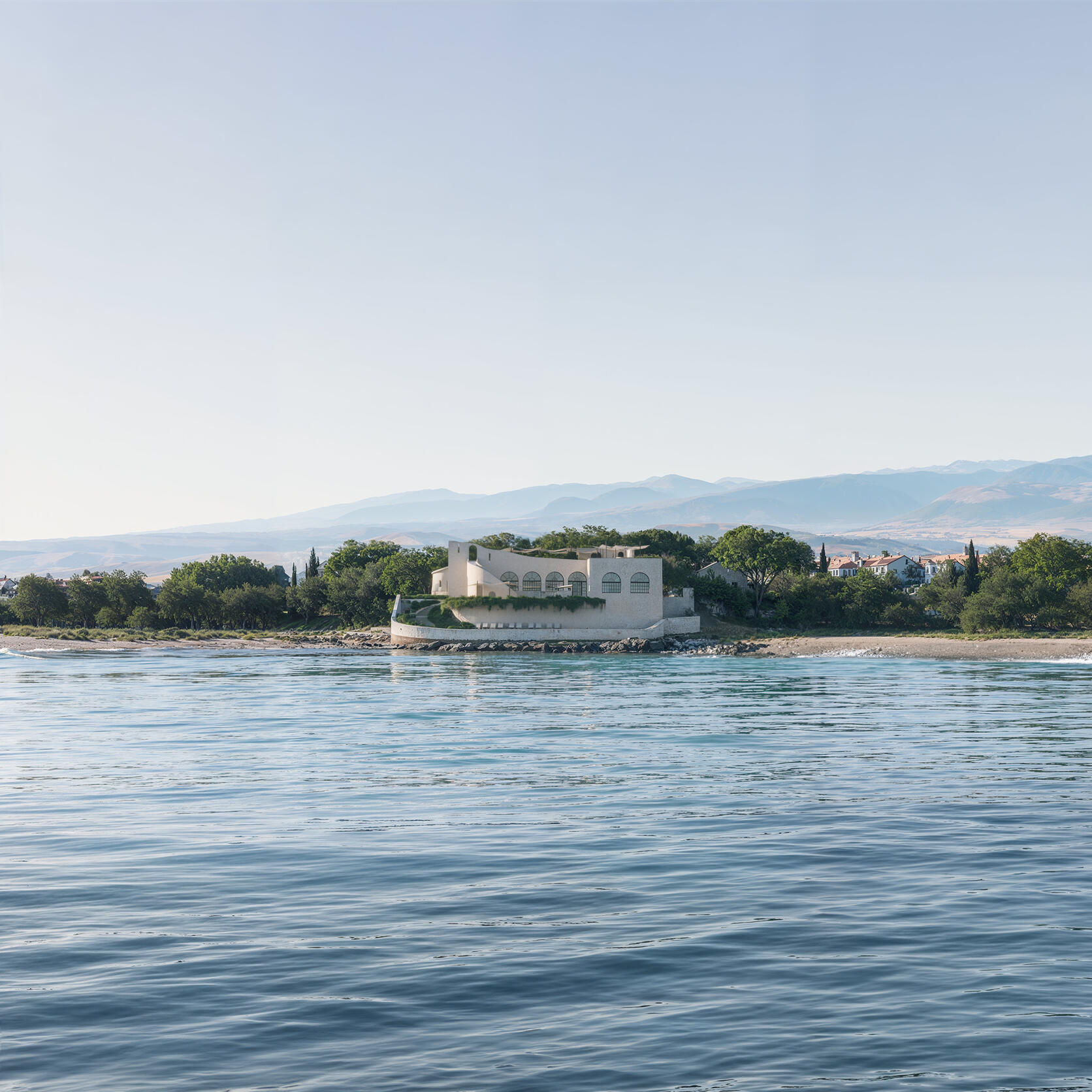 Photorealistic rendering of a coastal villa surrounded by trees, viewed from across calm water.