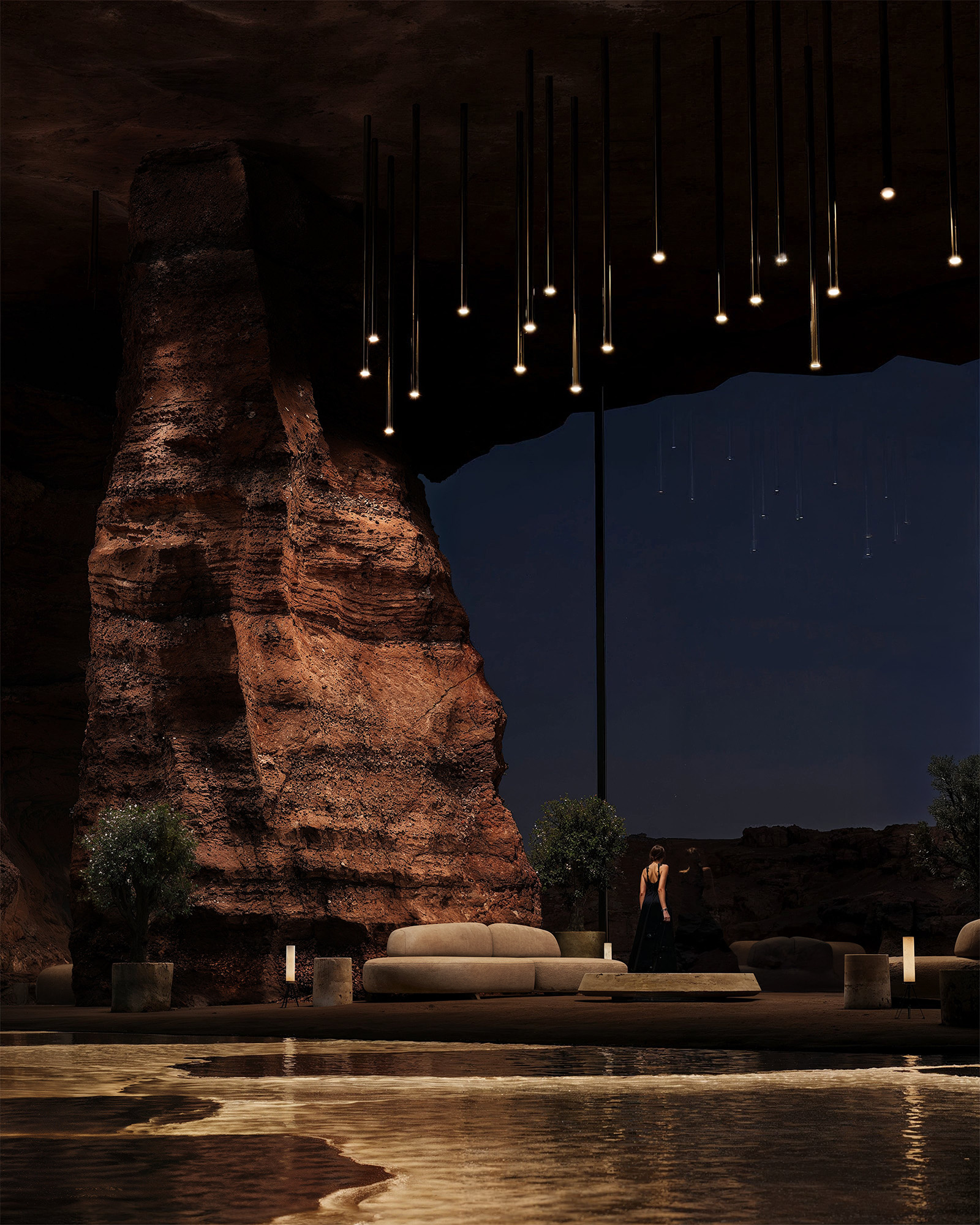 A dramatic lounge space set within a cavernous rock formation, featuring suspended pendant lights, sculptural furniture, and a reflective pool that glows softly under ambient lighting.